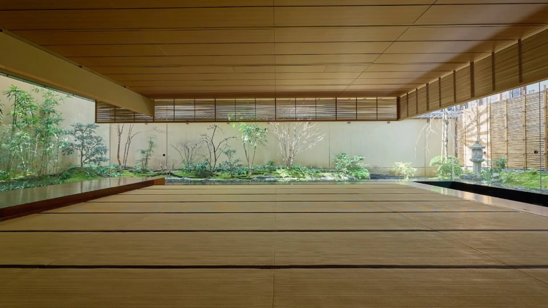 A pristine wooden engawa veranda extending toward a walled courtyard garden with carefully planted greenery and a stone lantern