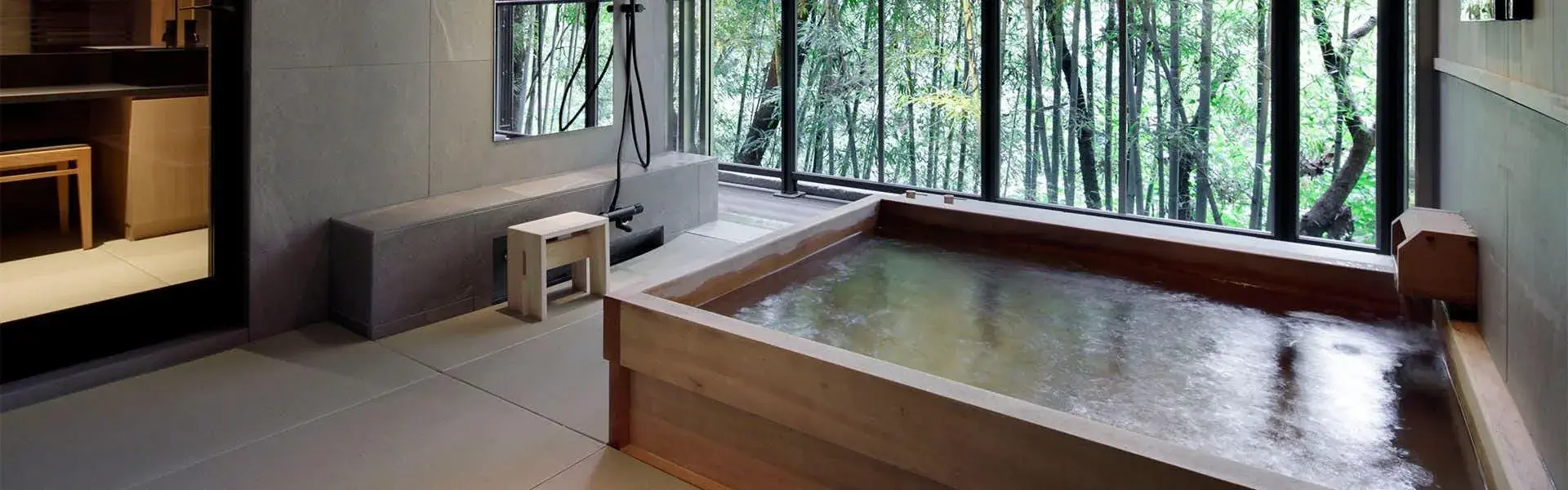 Hinoki wood soaking tub overlooking a bamboo grove at Higashiyama Onsen