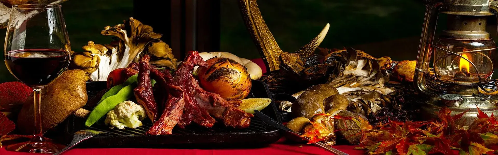 Autumn wild game platter with Nishiwaga forest mushrooms, antler, and red wine by lantern light