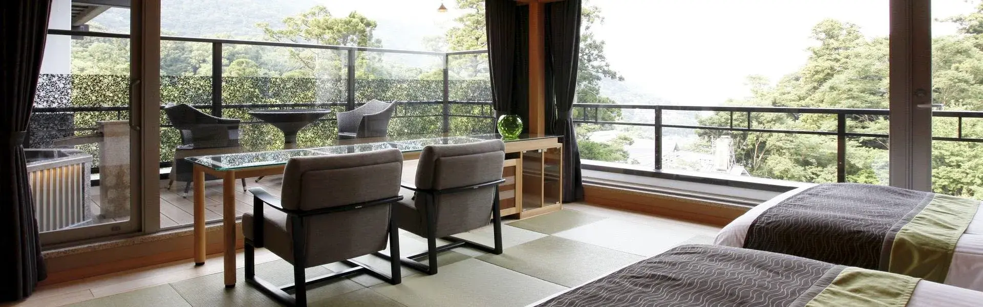 Tatami room with modern lounge chairs and forested mountain balcony view