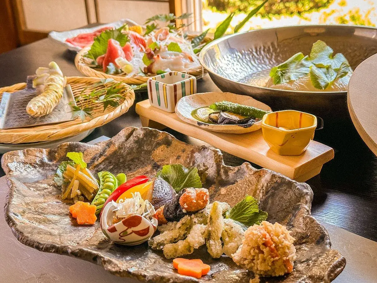 Onogiso kaiseki opening spread with tempura and sashimi on textured stone platter