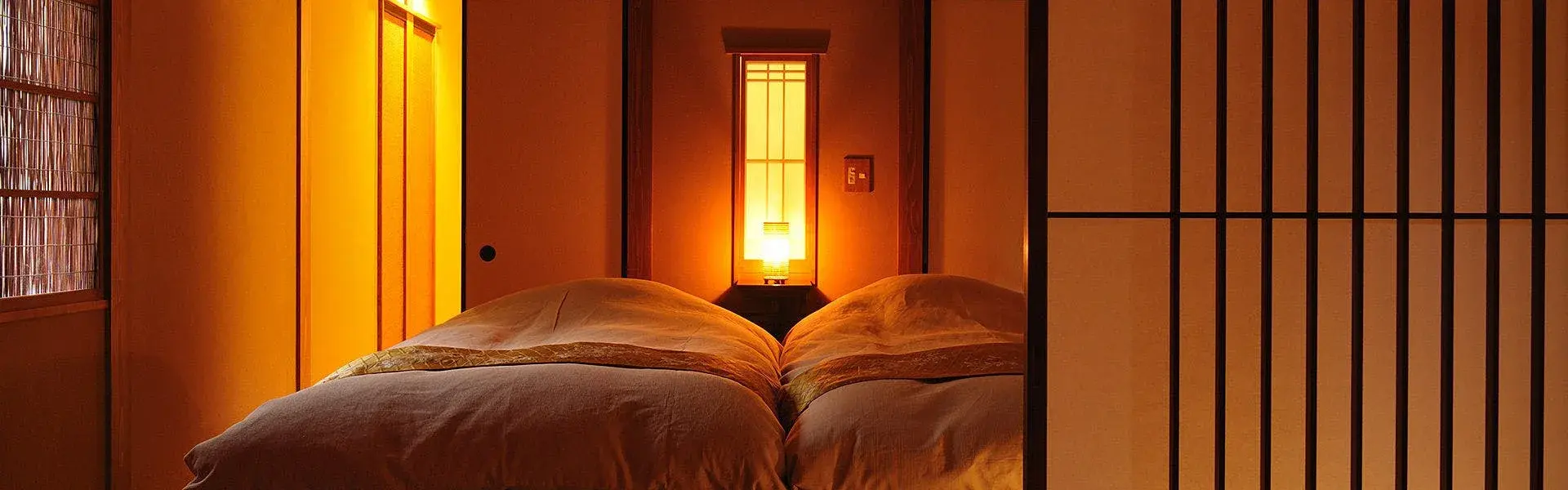 Twin futon beds framed by shoji screens and a warm paper lantern at Bettei Yaeno