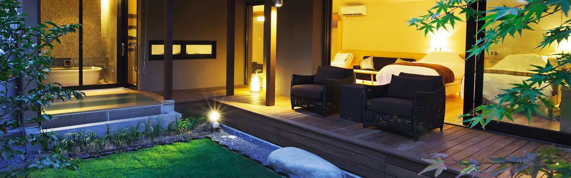 Private deck and stone outdoor bath at Tsukishiro in Misasa Onsen, lit at dusk