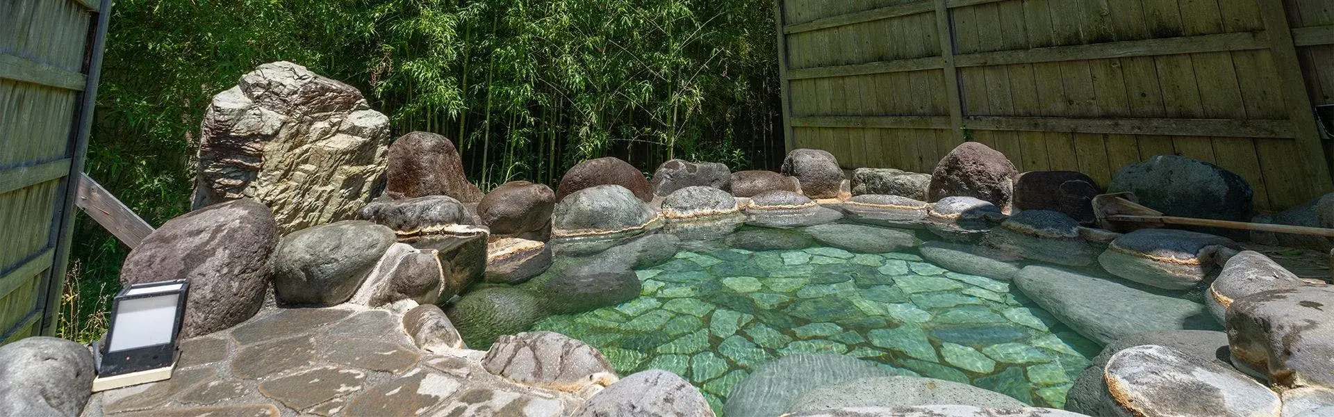 Rock-rimmed rotenburo outdoor bath enclosed by bamboo grove in Oku-Atagawa
