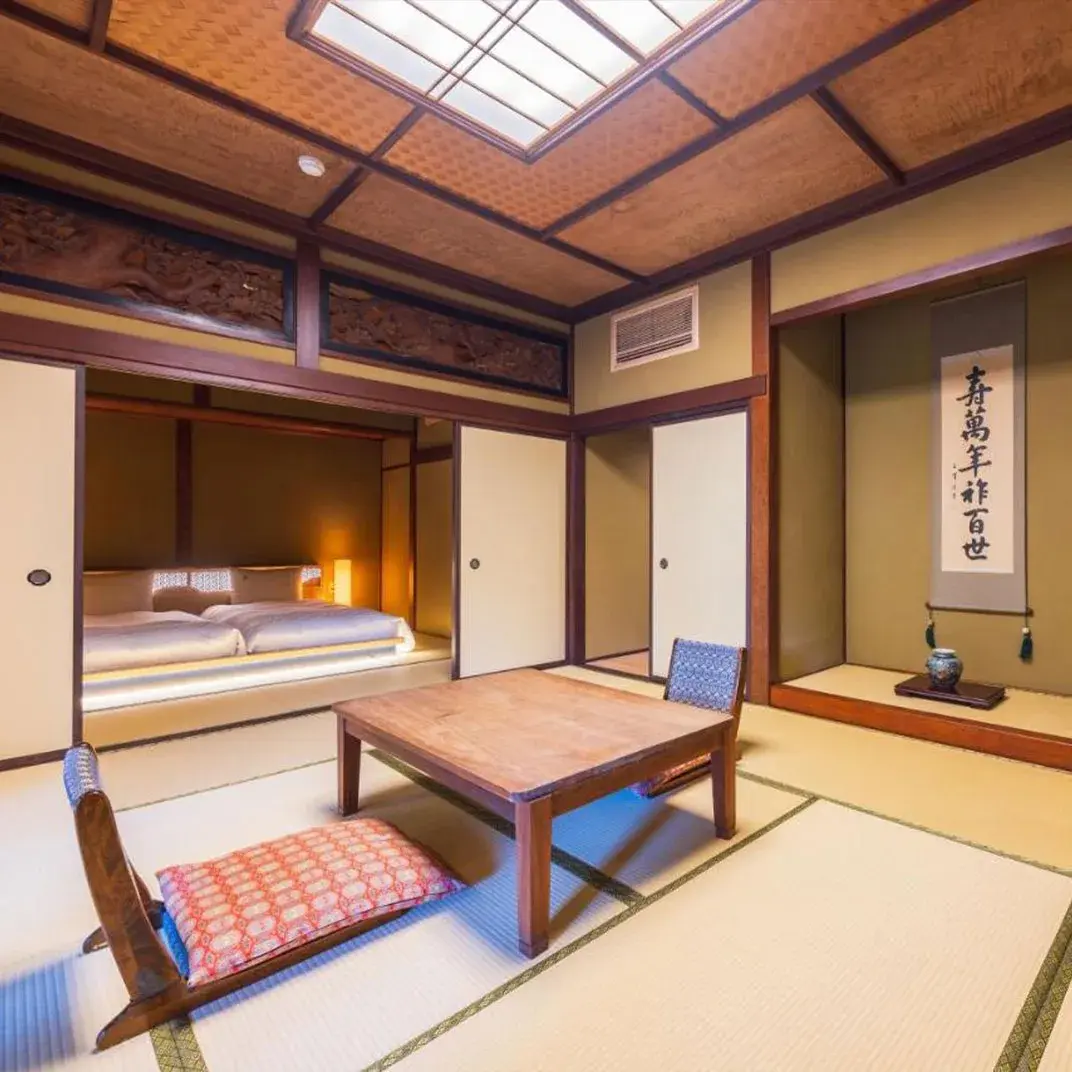Tatami room with carved wooden transom and calligraphy scroll tokonoma at Matsuzakaya Honten