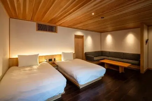 Twin room with cedar plank ceiling and dark hardwood floors at BYAKU Narai
