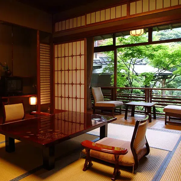 Tatami room with lacquered table and shoji screens opening to summer garden at Nishimuraya Honkan