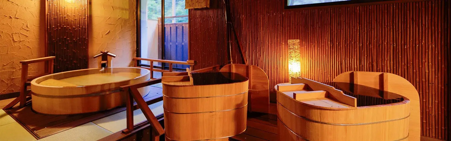Paired round hinoki barrel tubs in a candlelit private bath room