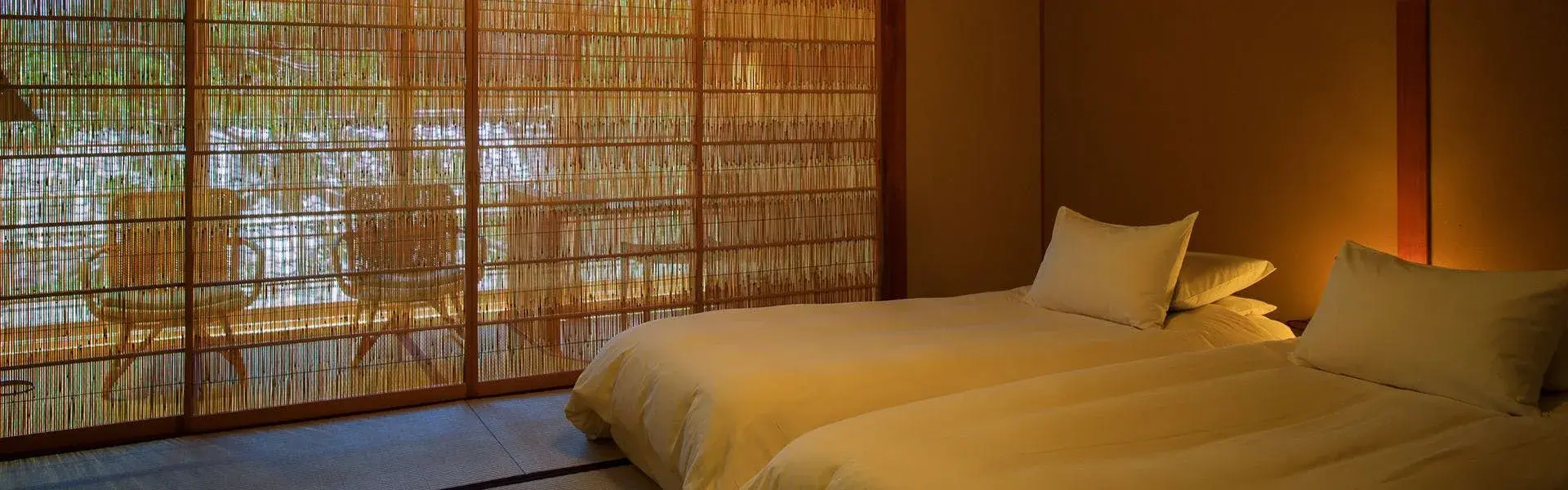 Twin beds beneath bamboo reed sudare screens in a Sekiyo guest room
