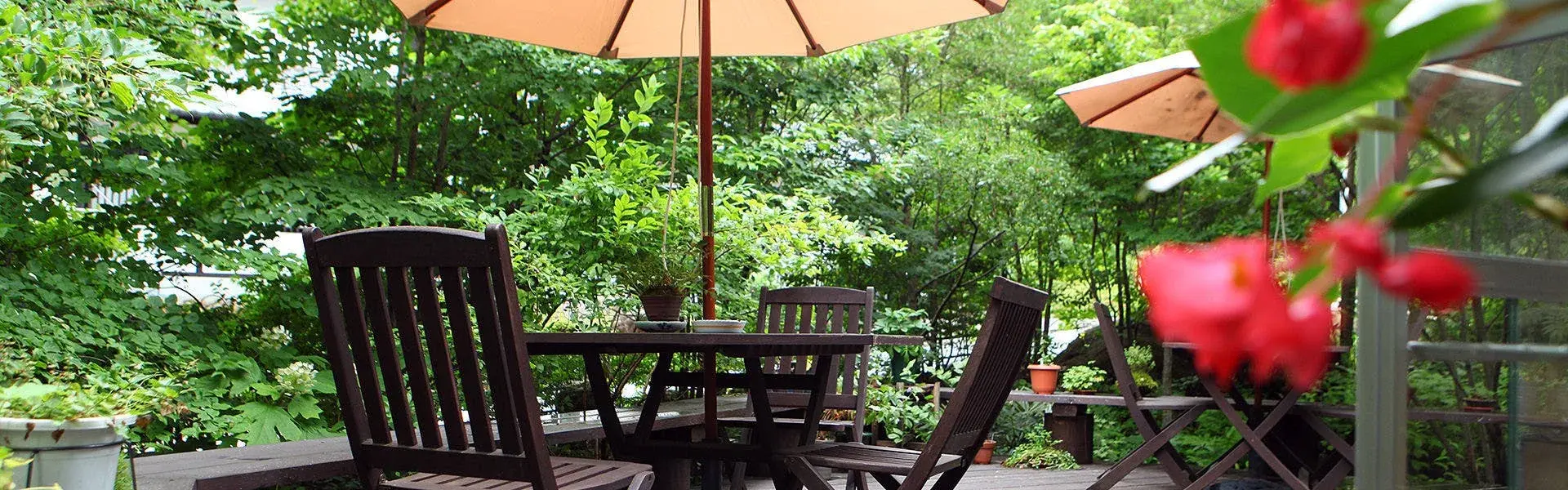 Outdoor terrace at Nishiya Villa shaded by parasols amid the Azumino cedar grove