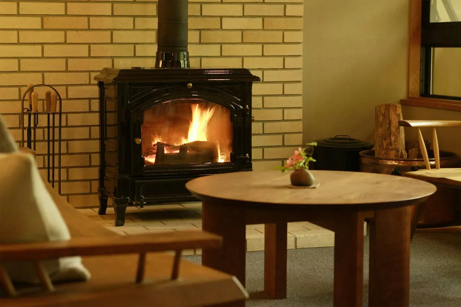 Cast-iron wood stove glowing in Oyado Nagomino's lounge, round cedar table alongside