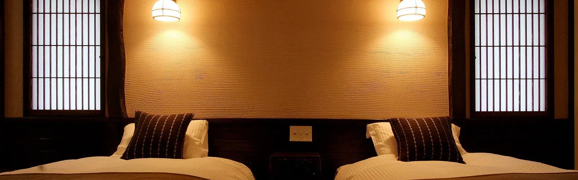 Twin bedroom with shoji panels and textured plaster wall at Auberge Hanabusa