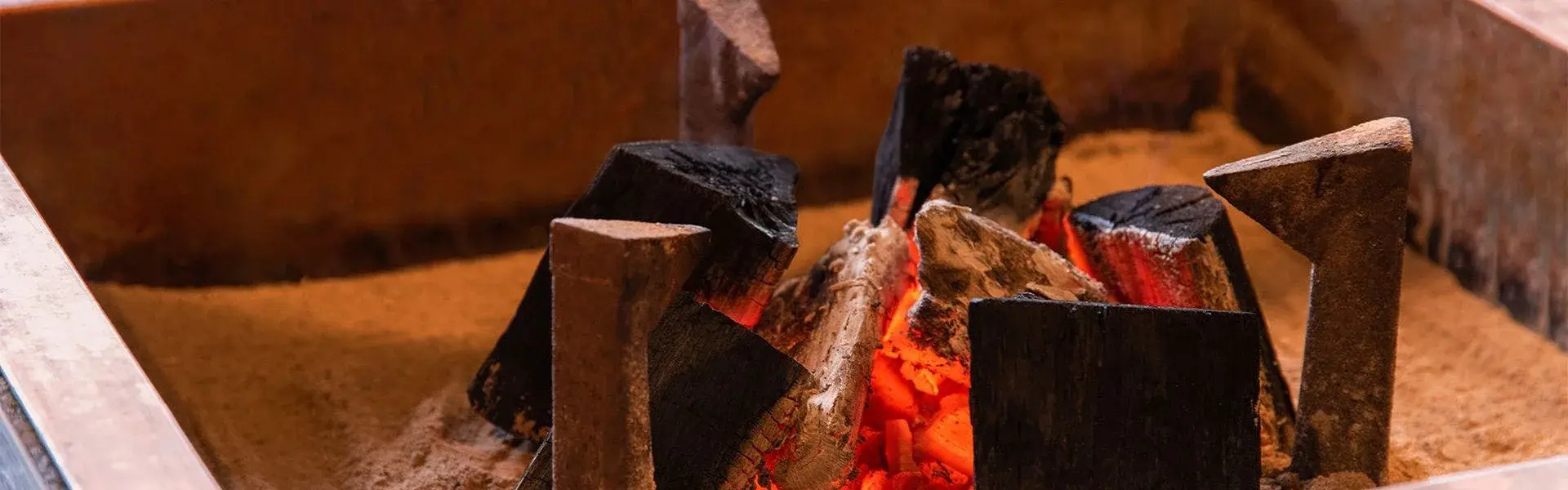 Glowing charcoal embers in Ryokan Hirobun's sand-filled irori firepit