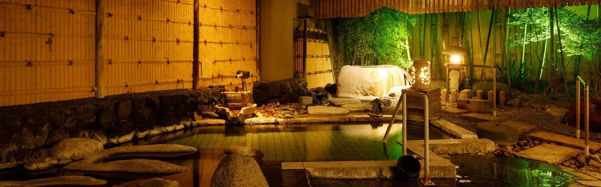 Rotenburo outdoor bath at night amid bamboo and stone lanterns at Tsuruya