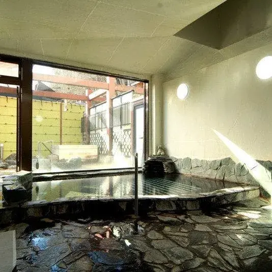 Steaming indoor stone bath looking out toward the outdoor terrace at Yunishigawa Onsen