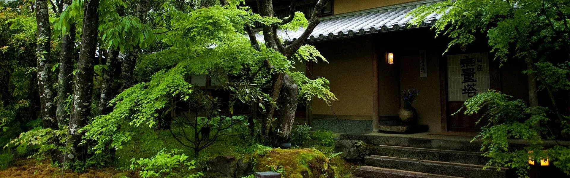 Sansou Murata's moss-lined entrance beneath fresh-green maple canopy in Yufuin