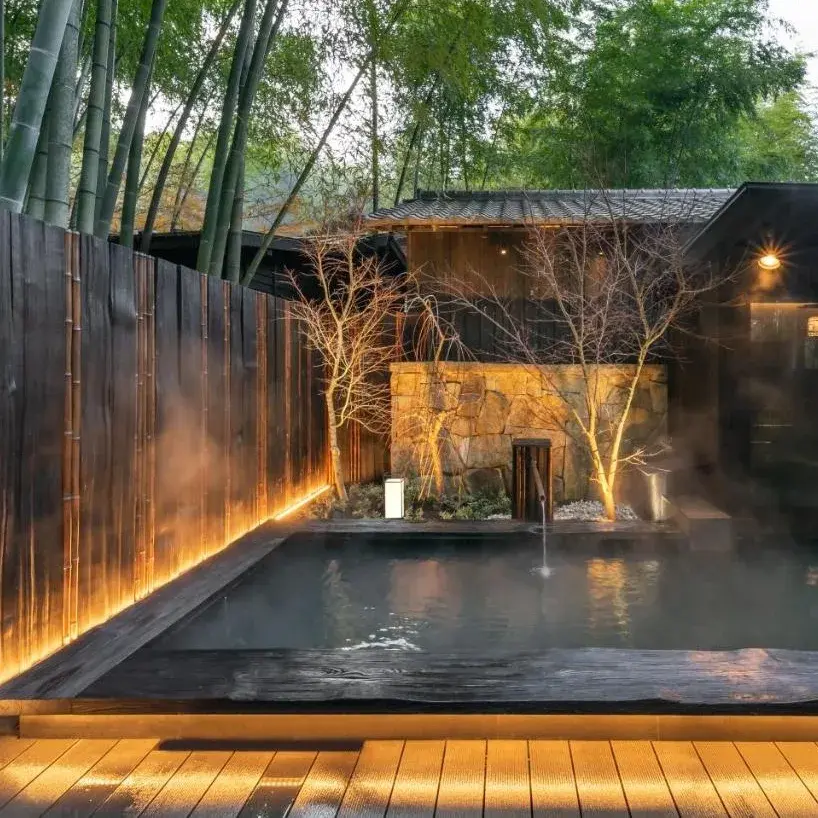 Steaming rotenburo at Takefue with lit bamboo grove at dusk in Minamioguni