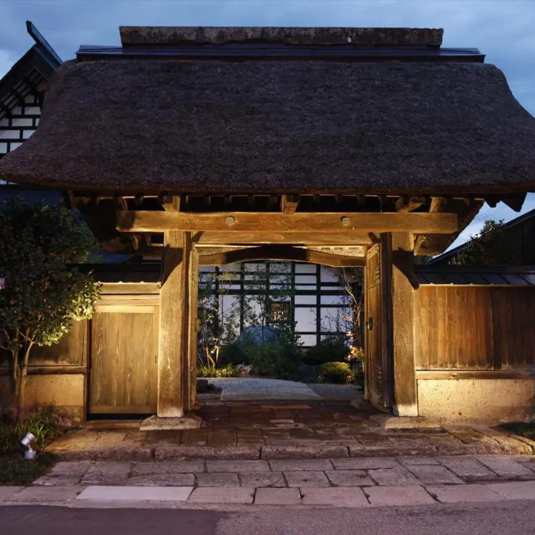 Takinami's 400-year-old thatched timber gate at Akayu Onsen, lit at dusk