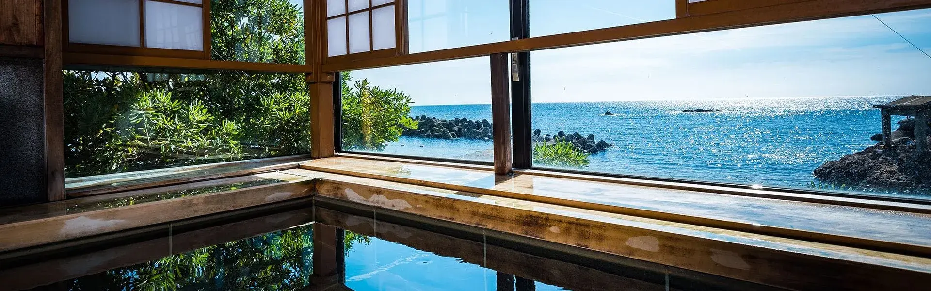 Indoor onsen bath at Yamazaki opening onto the Echizen Coast through wooden-framed windows
