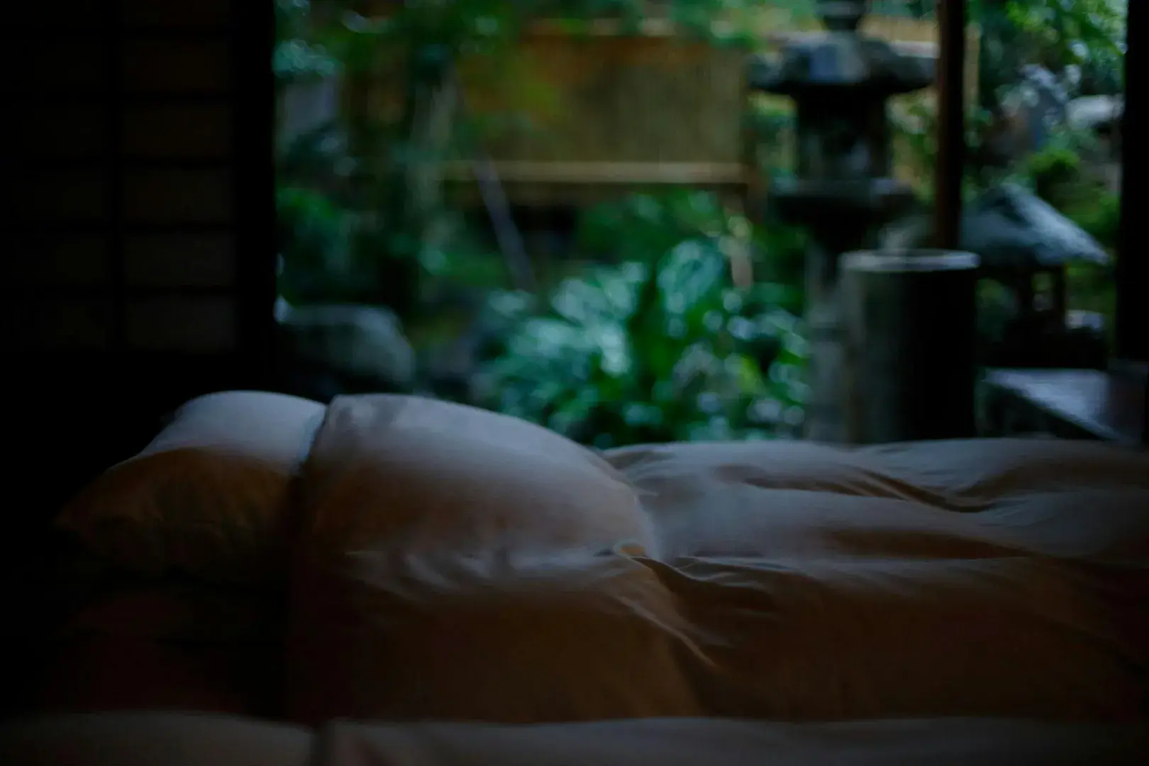 Futon bedding with stone lantern garden glimpsed through open screens at Hatago Wakatsu