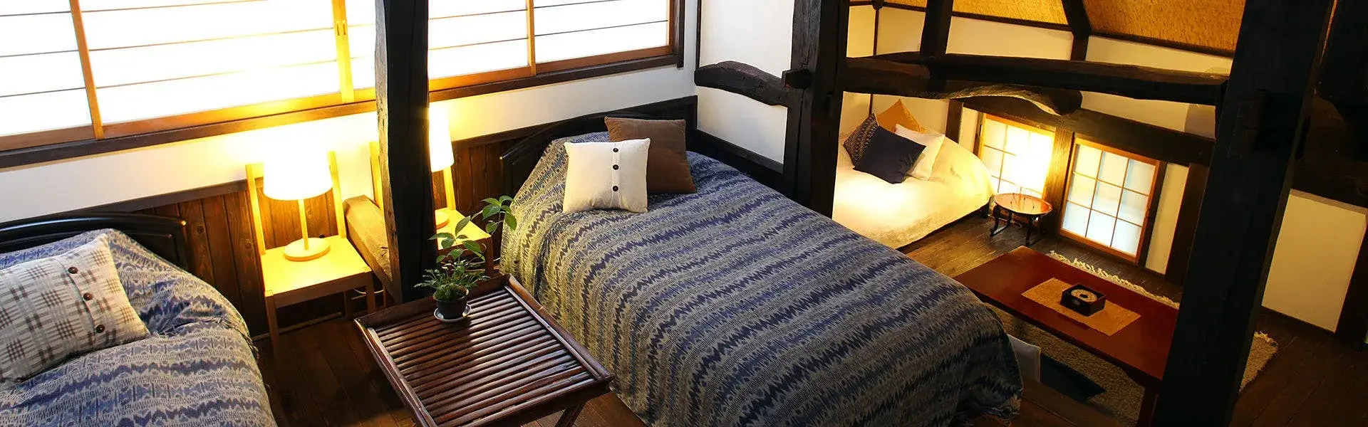 Nishiya Villa's farmhouse bedroom with smoke-darkened beams and indigo patterned coverlets
