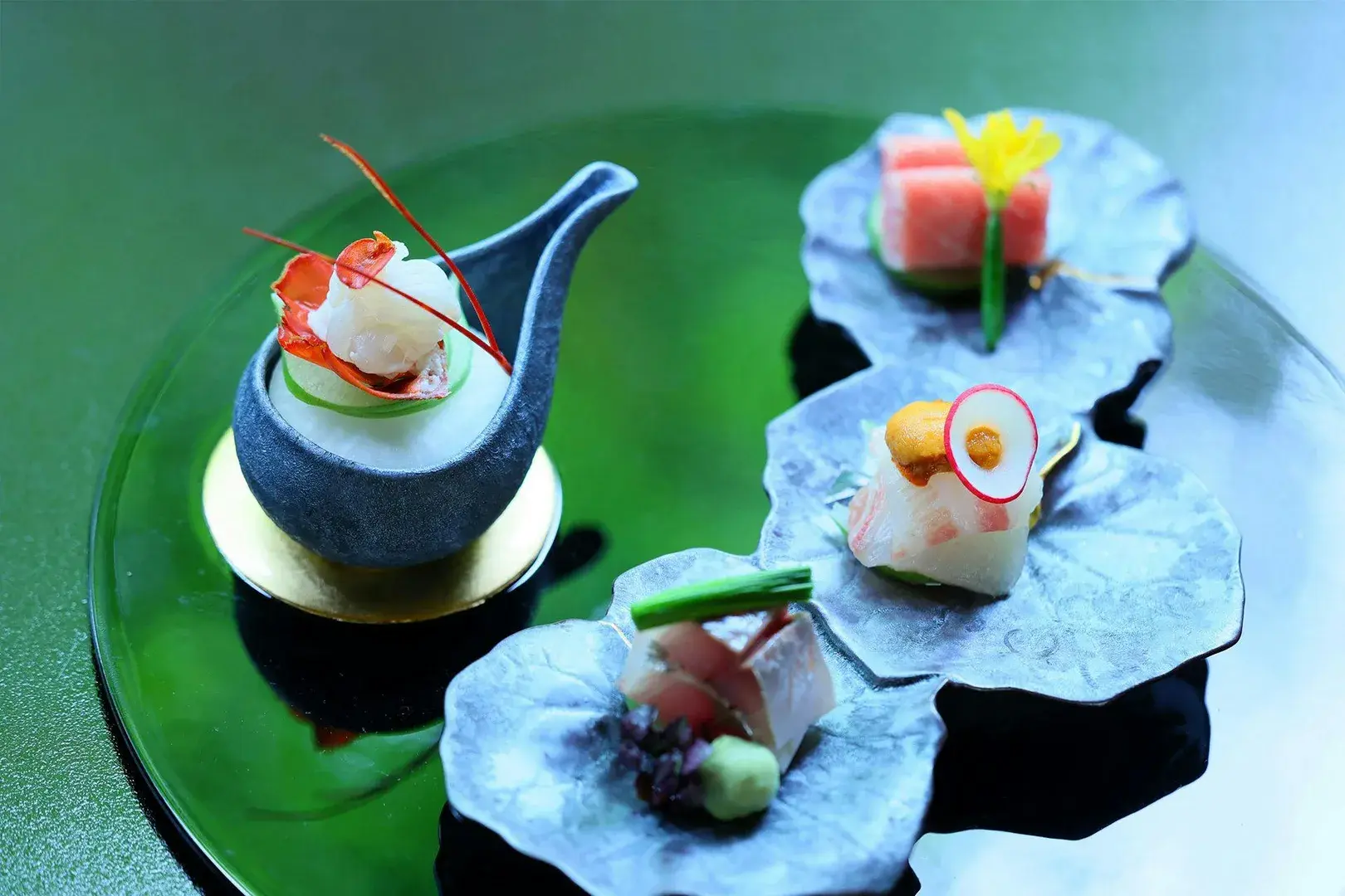 Kaiseki opening bites on sculptural leaf dishes and ceramic spoon at Tsutsuji-tei