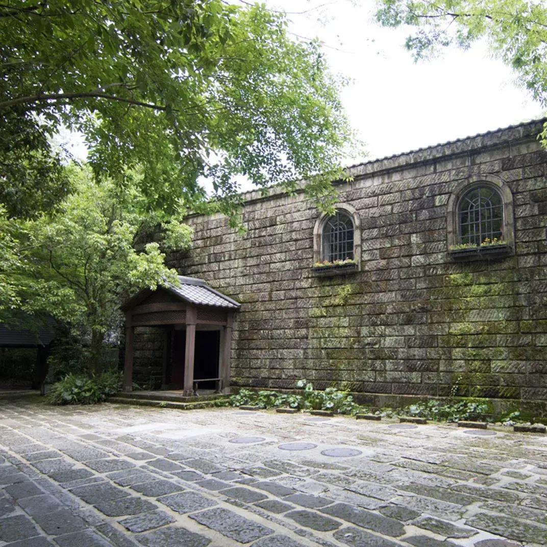 Moss-covered stone bathhouse walls and cobblestone courtyard at Myoken Ishiharaso