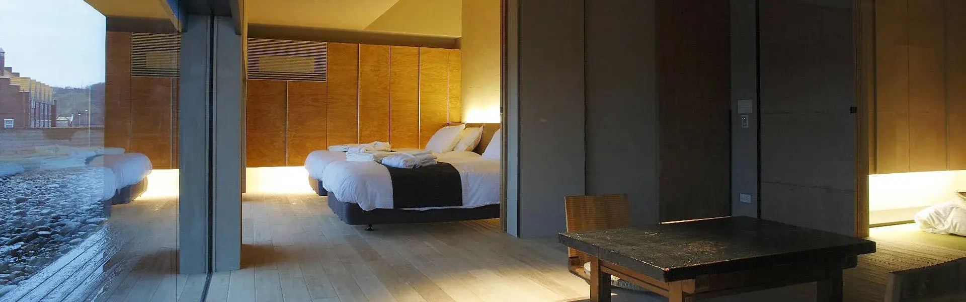 Ryotei Kuki guest pavilion with floor-to-ceiling glass and twin beds overlooking stone garden