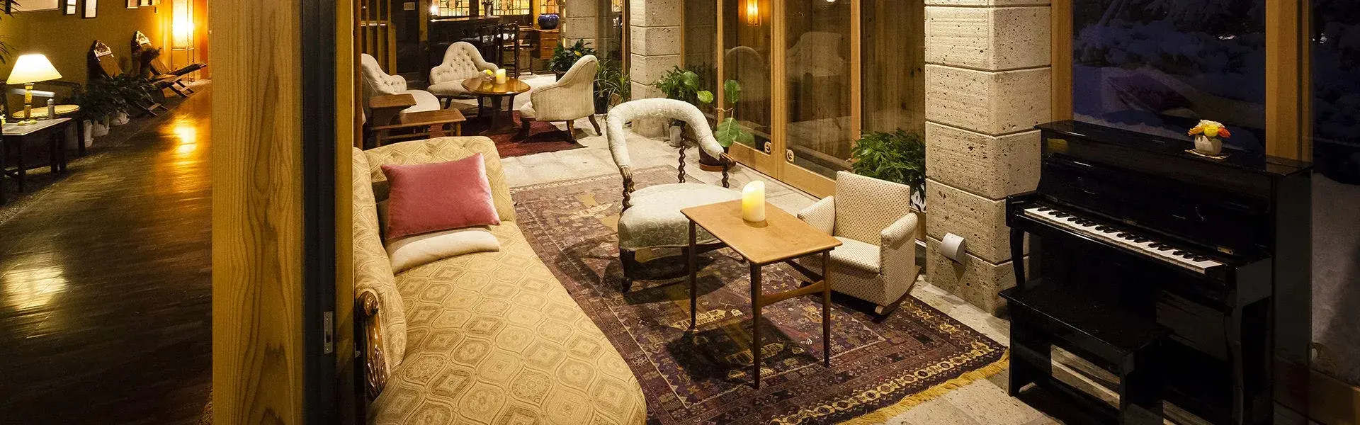 Lobby lounge at Meigetsuso with vintage armchairs, Persian rug, and upright piano