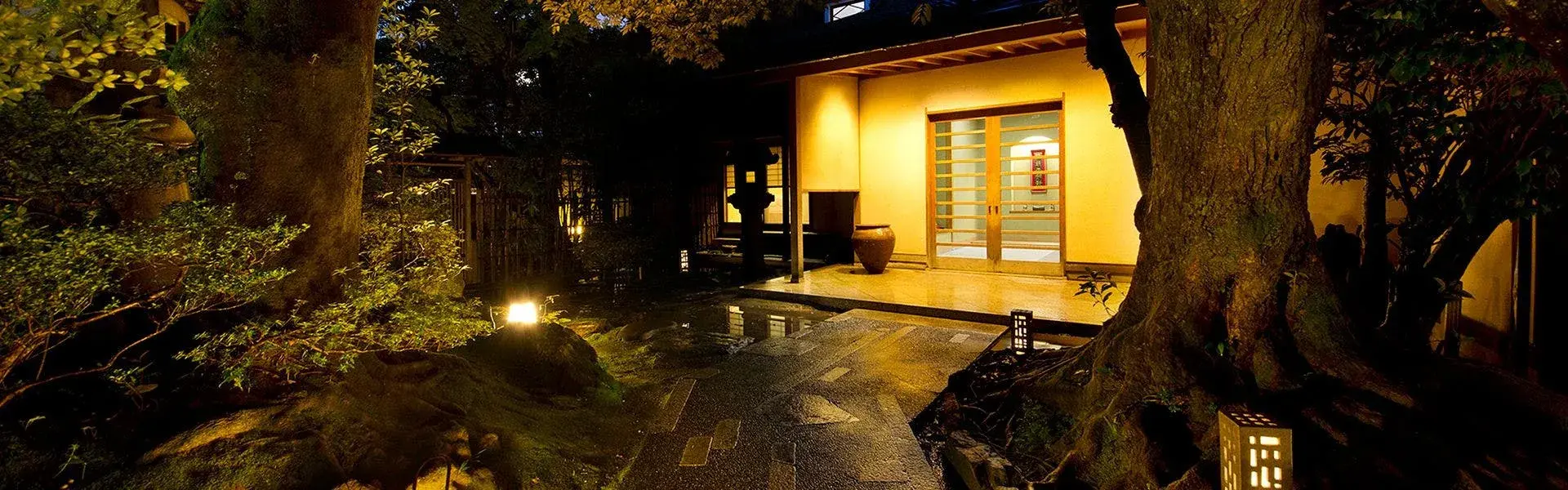 Kocho's stone garden path lit by lanterns at dusk in Yamanaka Onsen