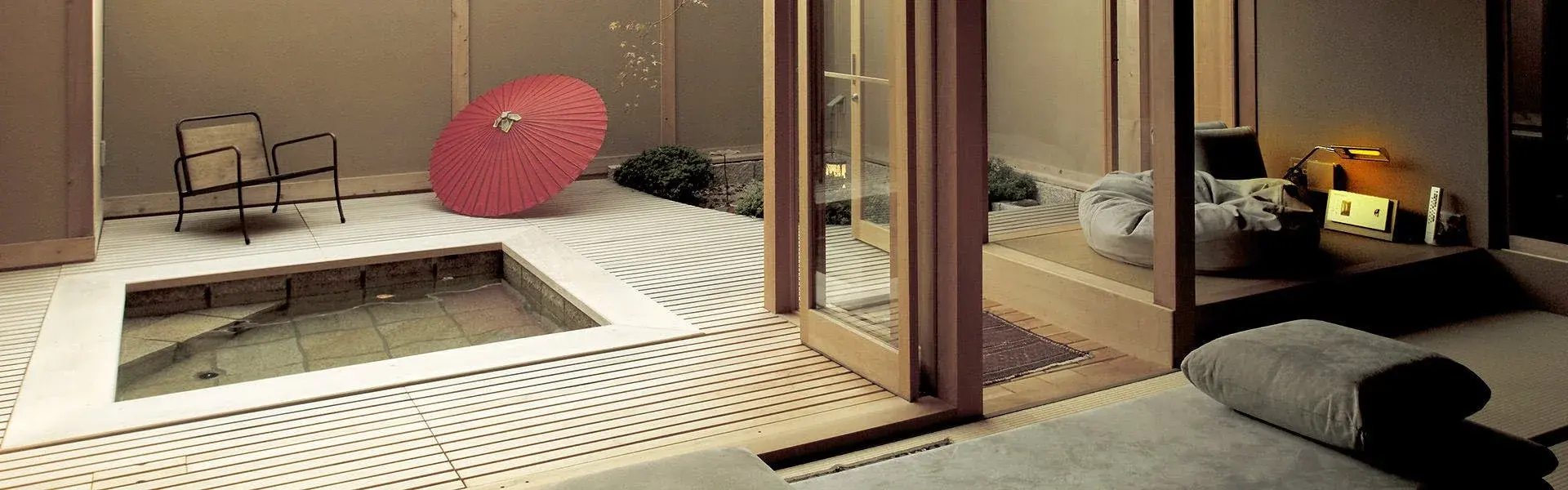 Private rotenburo terrace with cedar deck and red wagasa parasol at Miyahama Onsen