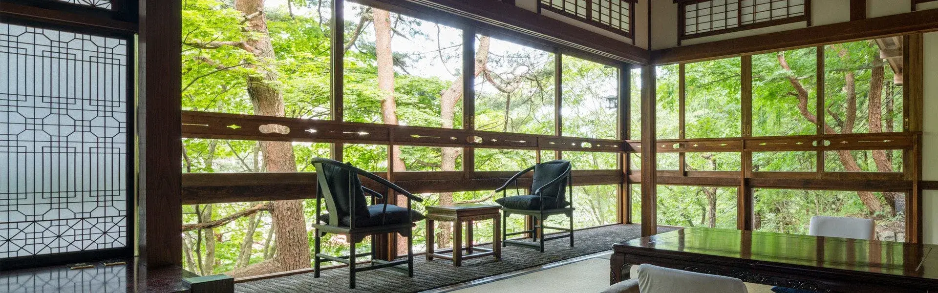 Kashoutei sitting room with floor-to-ceiling wood-framed windows into Shima Onsen forest