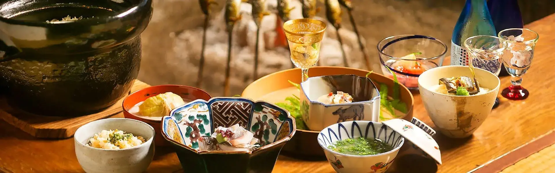 Kaiseki dinner spread at Wada-ya with river fish skewers, lacquerware bowls, and chilled sake