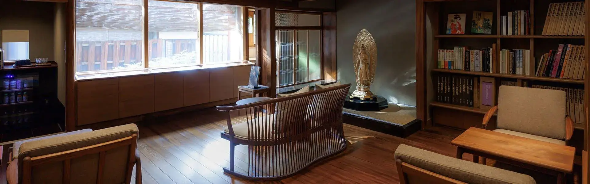 Reading lounge with golden Buddha statue and bookshelves at Hiiragiya Ryokan