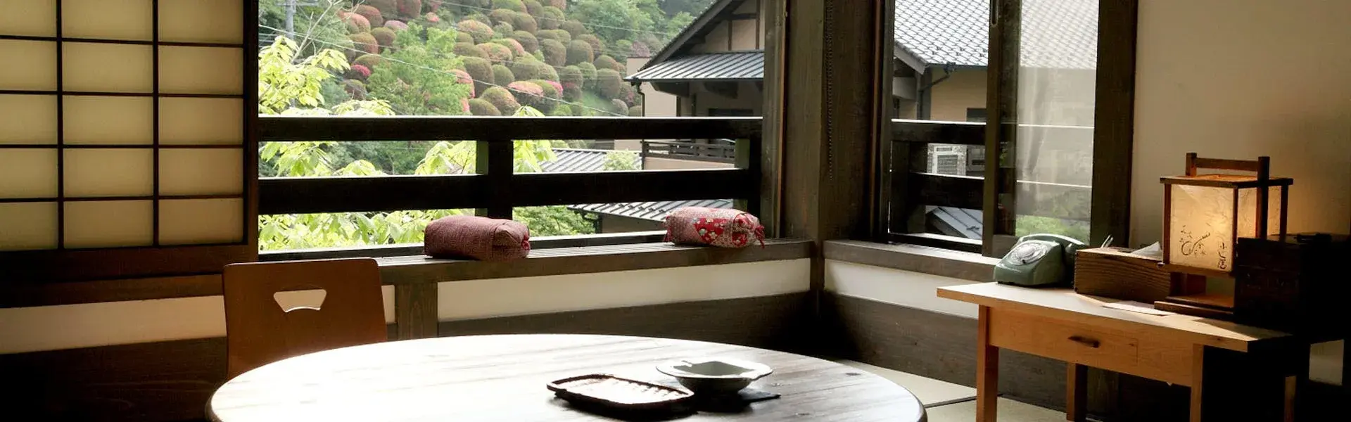 Window seat overlooking manicured green shrubs in a Fujiya tatami sitting room