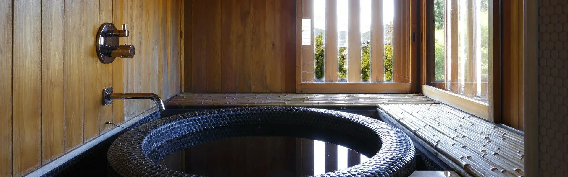Circular mosaic-tile in-room bath enclosed in cedar wood with slatted shoji window