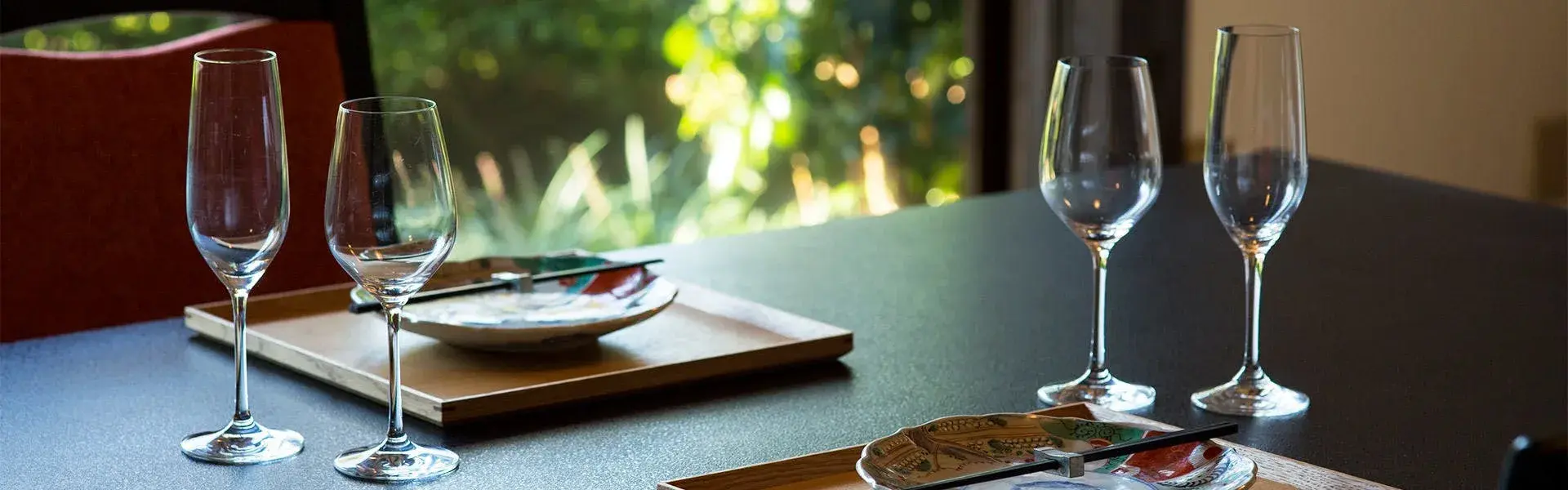 Wine glasses set for dinner, Ito garden framed in the window