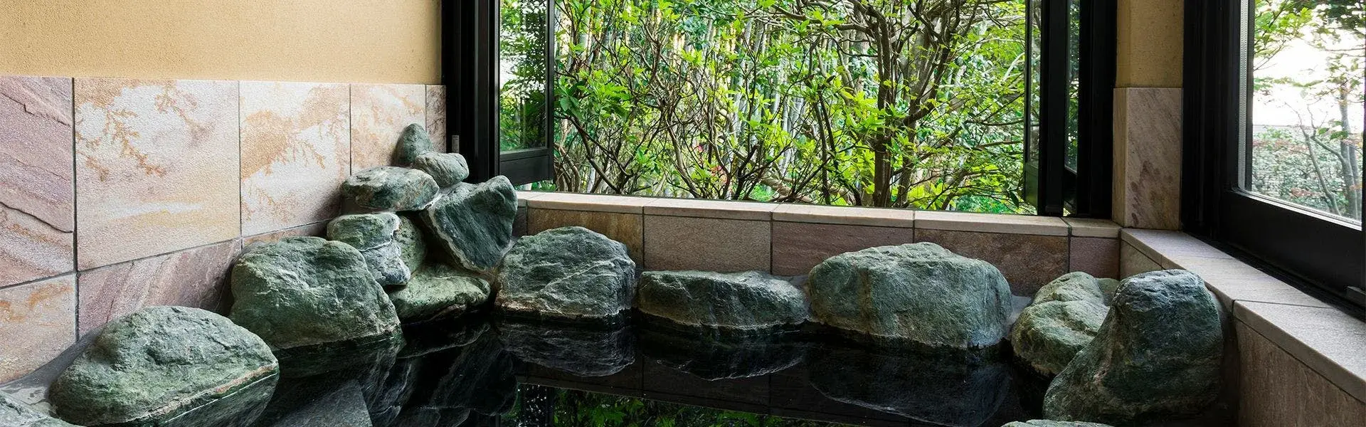 Indoor stone bath at Izu no Hana with boulders and forest view in Futo