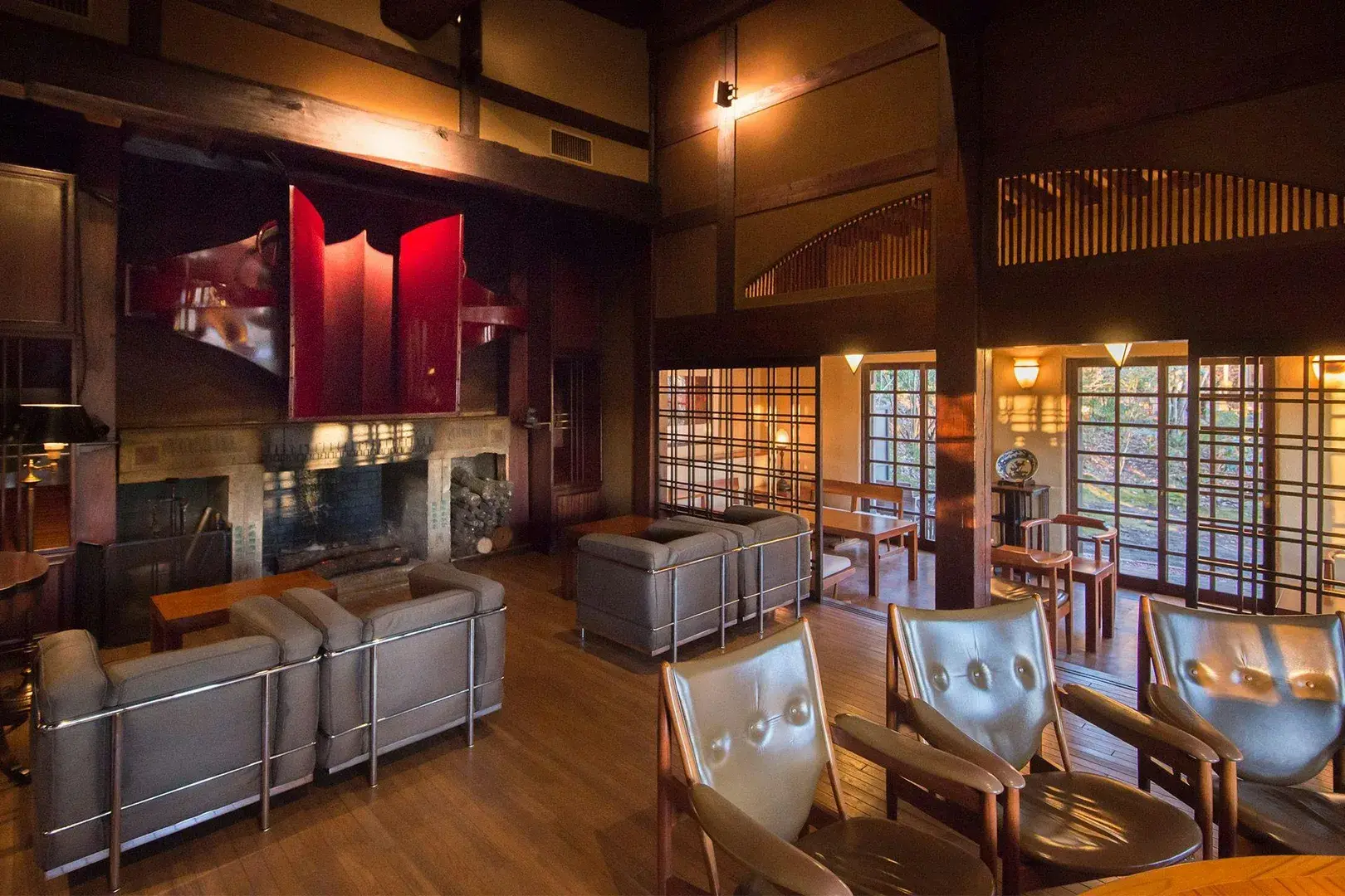 Timber-ceilinged bar lounge with Le Corbusier leather chairs and stone fireplace