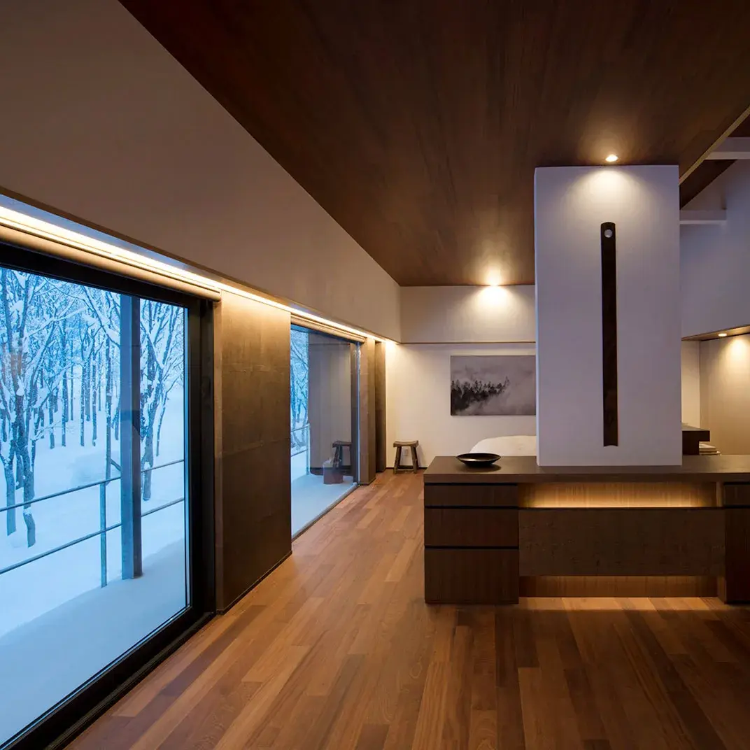 Villa interior at Zaborin with dark timber ceiling and floor-to-ceiling windows framing a snow-covered birch grove