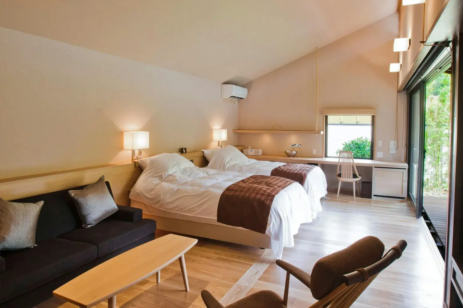 Suite bedroom with vaulted pale wood ceiling and garden-facing sliding doors at Tsukishiro