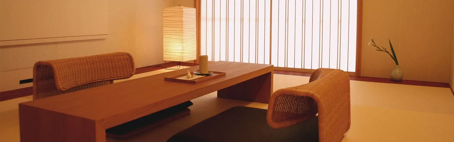Tatami sitting room with low walnut table, rattan zaisu chairs, and shoji screens