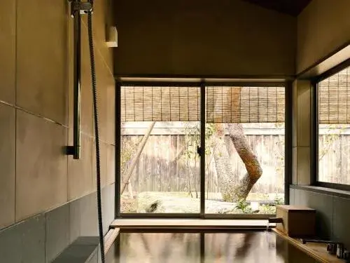 Private hinoki bath opening to a bamboo-screened garden at Kofuyuden Beniya