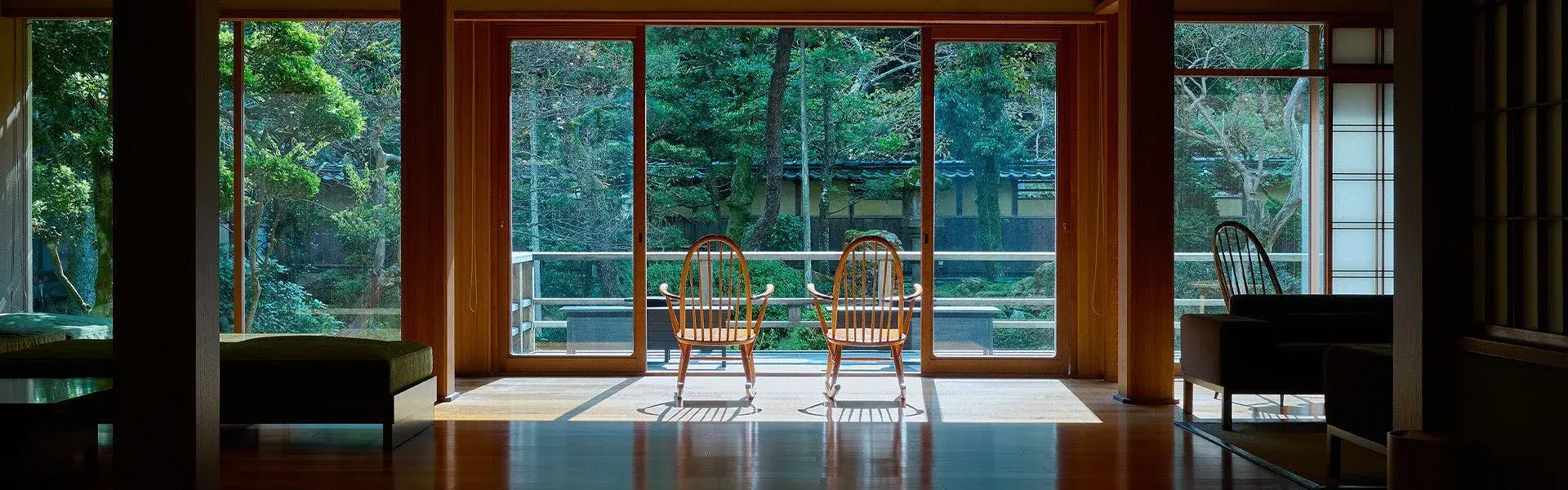 Two Windsor chairs face Mikiya's garden through floor-to-ceiling timber windows