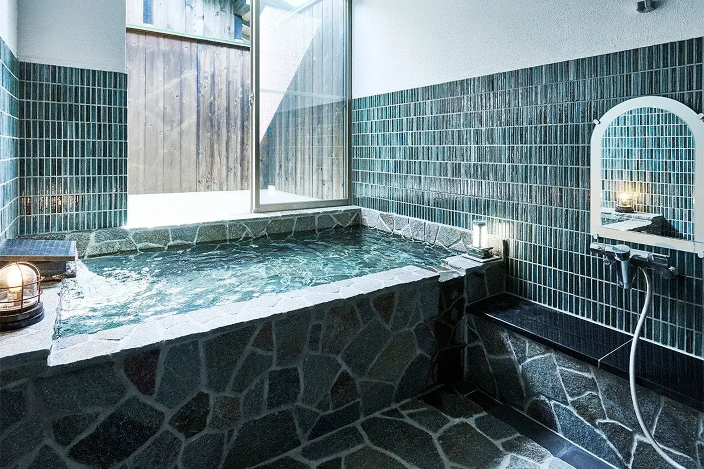 Private indoor onsen bath with teal mosaic tile walls and stone floor at Taikanso
