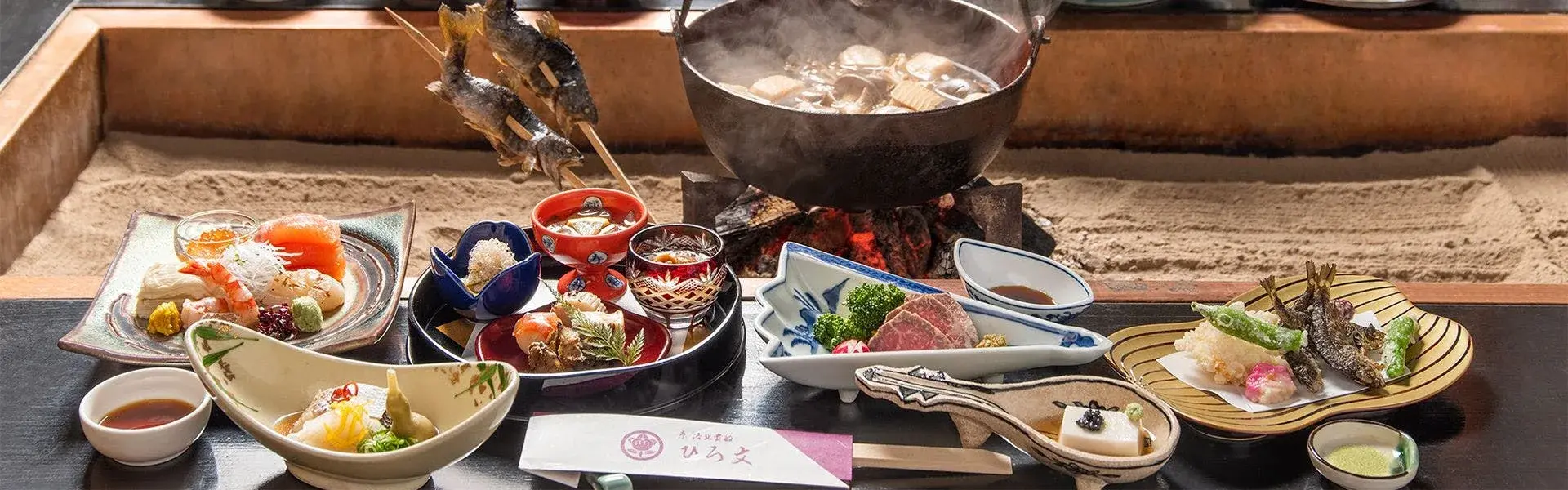 Hirobun's kaiseki dinner spread around an irori hearth, whole ayu on skewer, Kibune Kyoto