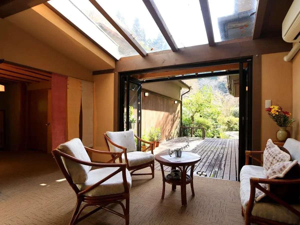 Rattan lounge chairs and skylight open to a forested Yoshino hillside
