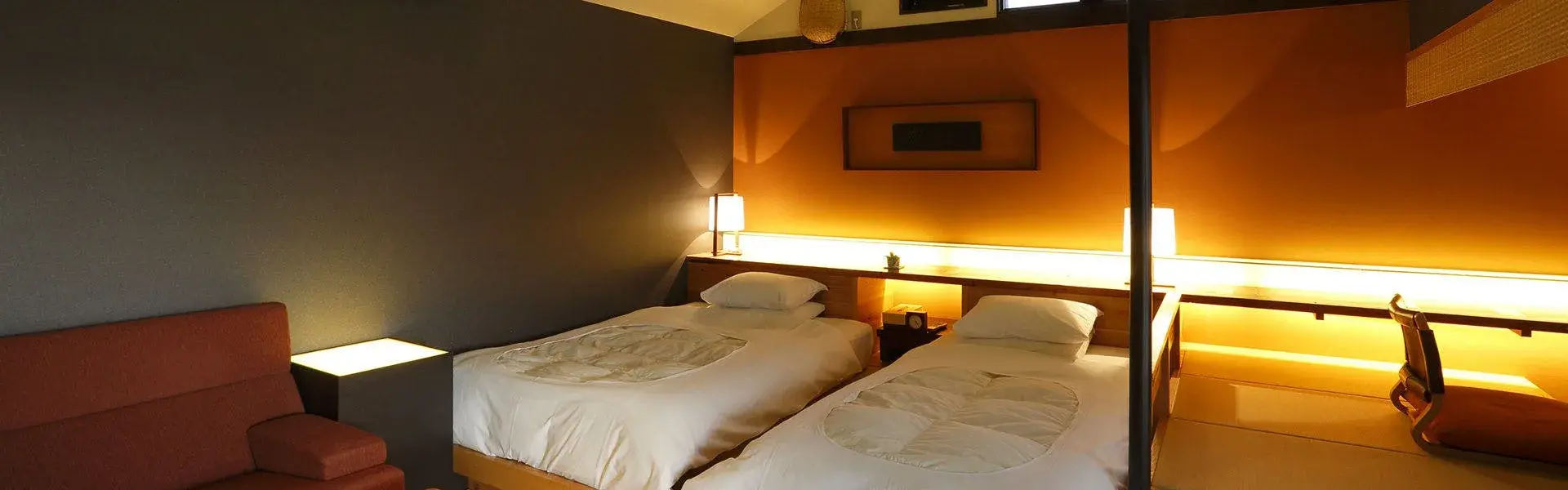 Twin bedroom with warm amber lighting and white linens at Mari