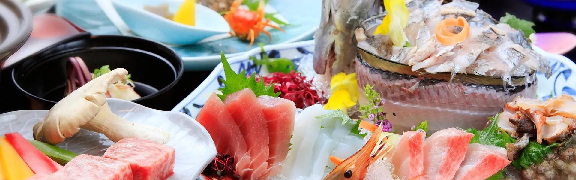 Kaiseki sashimi spread with tuna, shrimp, and whole fish on blue-and-white ceramics