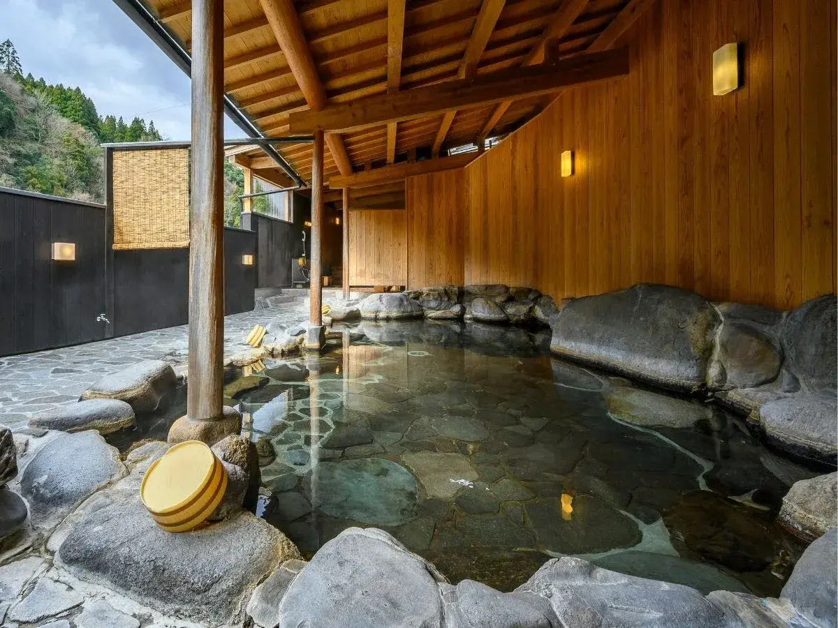 Outdoor rotenburo with cedar paneling and river stones at Misasa onsen